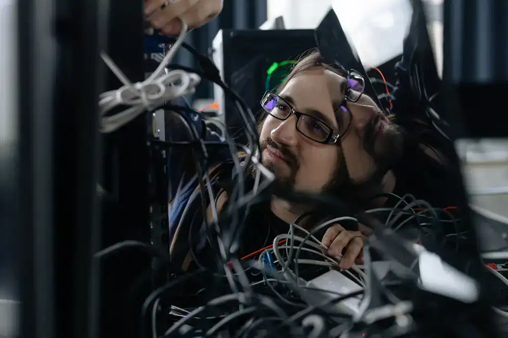 Technician routing cables behind a streaming desk
